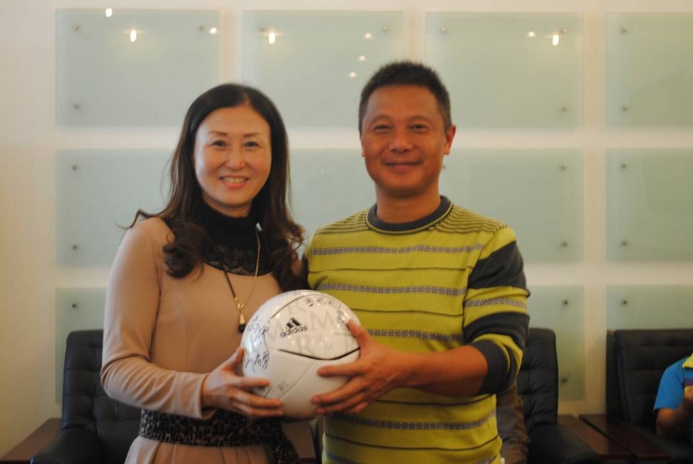 队长胡悦代表校友们为母校赠送每位队员签名的足球.jpg